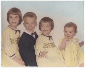 photo of Tierney kids circa 1969. The girls are all dressed in yellow dresses with black ribbon ties at the neck and sleeves, the boy is dressed in a dark suit with a white shirt and bow tie